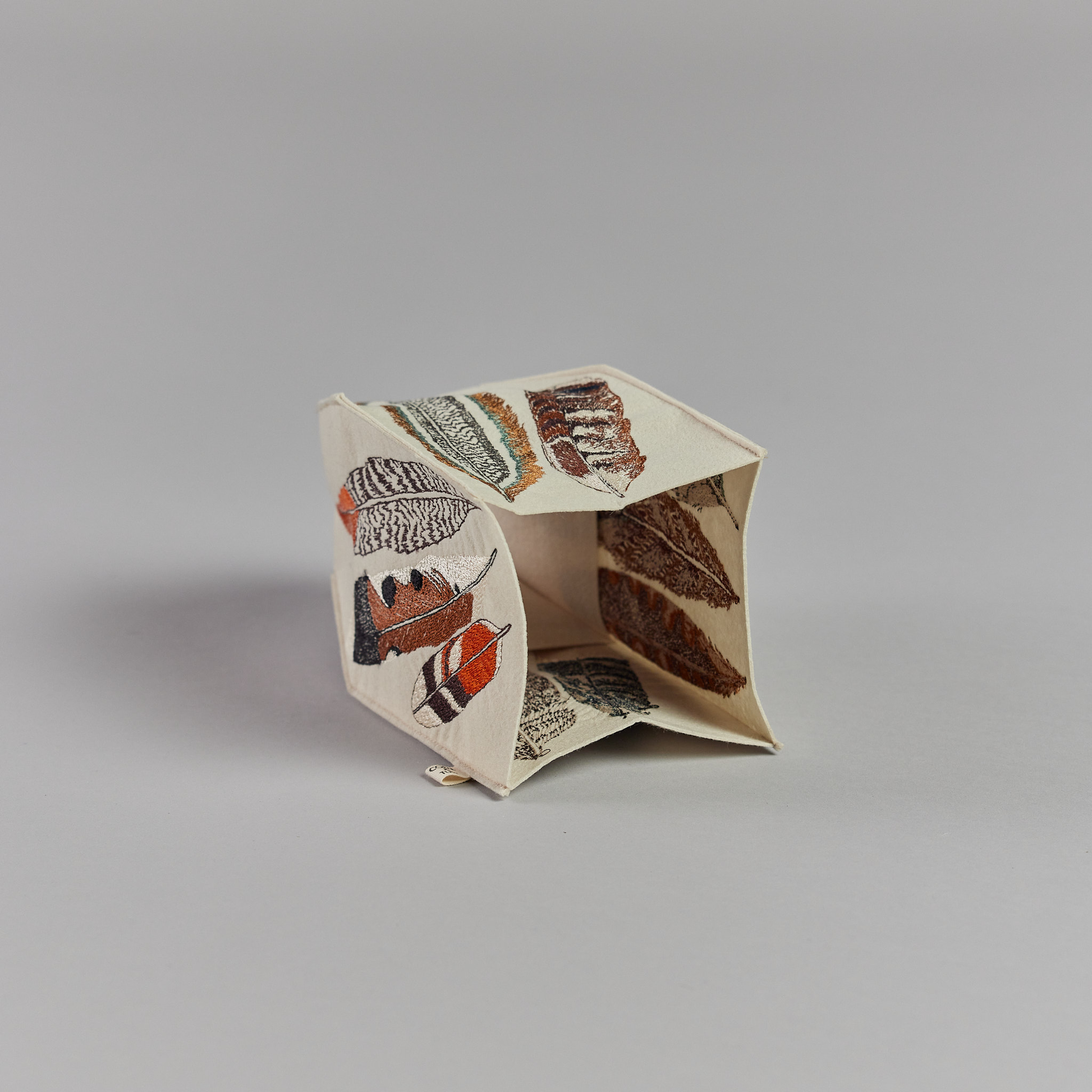 Coral and Tusk's "Feathers" tissue box cover made of felt and embroidered with a varied feather design