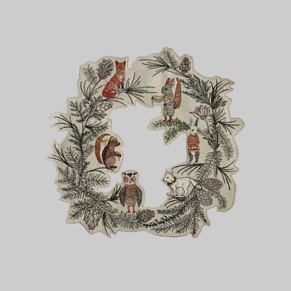Coral and Tusk's "Tree Trimmers" embroidered holiday wreath featuring intricate pine needle designs and animal friends