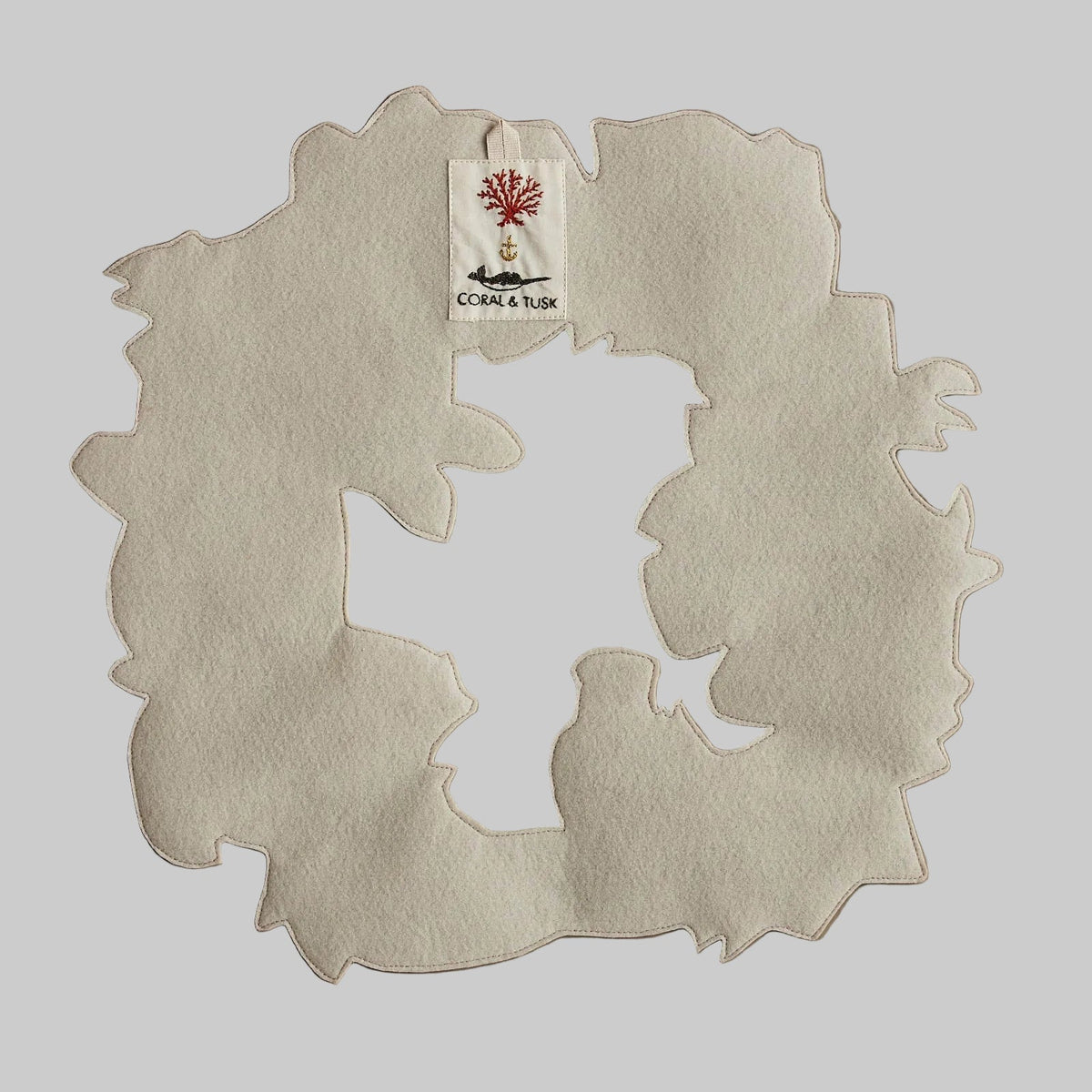 Coral and Tusk's "Tree Trimmers" embroidered holiday wreath featuring intricate pine needle designs and animal friends
