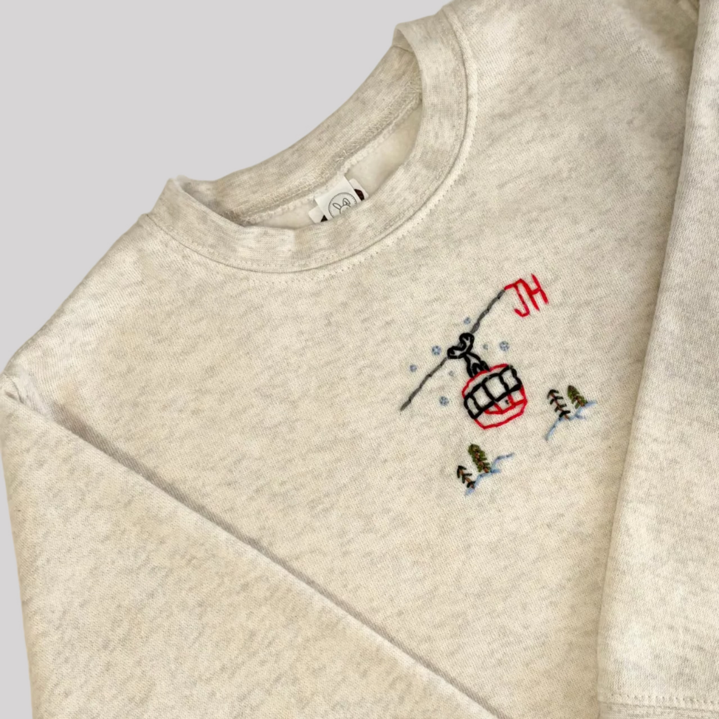 Roam Wild Good’s hand-embroidered kids sweatshirt in oatmeal with a ski gondola design inspired by Jackson Hole, Wyoming