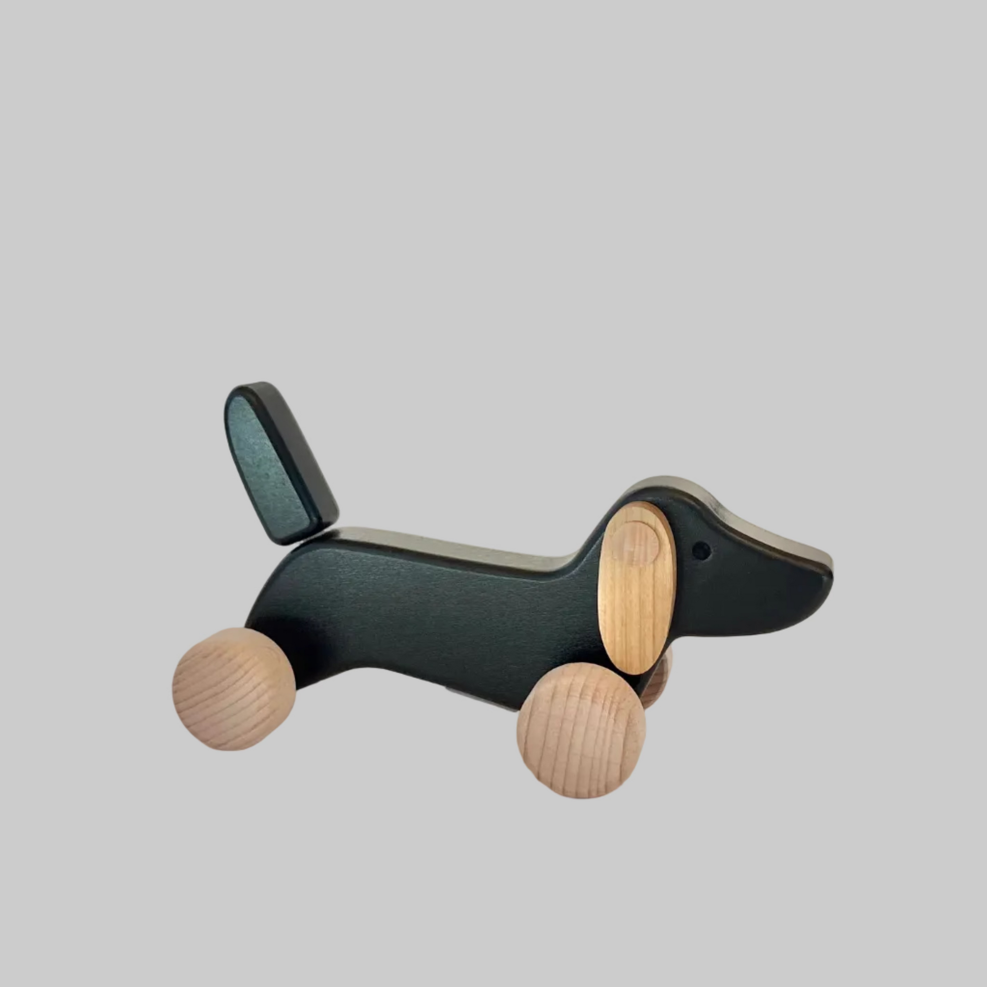 Little Poland Gallery’s wooden toys featuring a black dachshund on wheels and spinning ears